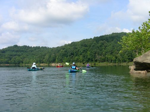 Kayaks paddle near a rock cliff
