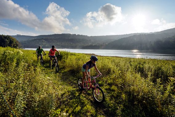 A group of Mountain Bikers make their way around the lake on a cross country trail