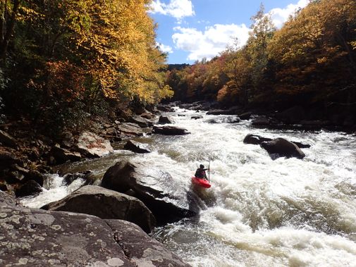A kayaker boofs off a rock and over a hole on the Upper Yough River
