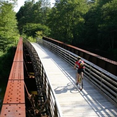 A cyclist crosses a bridge on the West Fork Trail