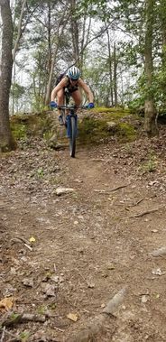 A mountain biker rides a small rock ledge at Upshur County Trails