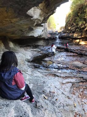 Three hikers explore the waterfall streambed at White Park