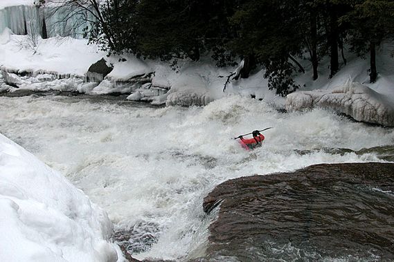 A kayaker goes over Swallow Falls in the winter
