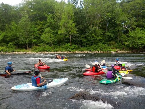 A group of kayakers practice surfing on the Middle Yough River