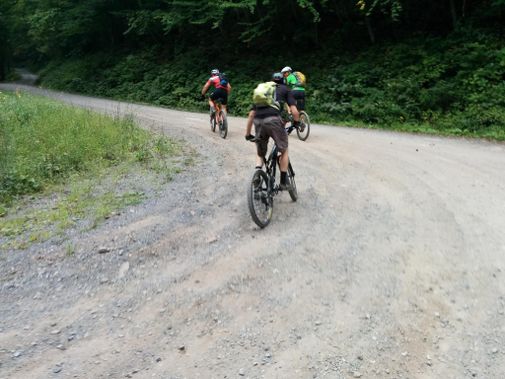 Mountain bikers ride up a steep gravel road