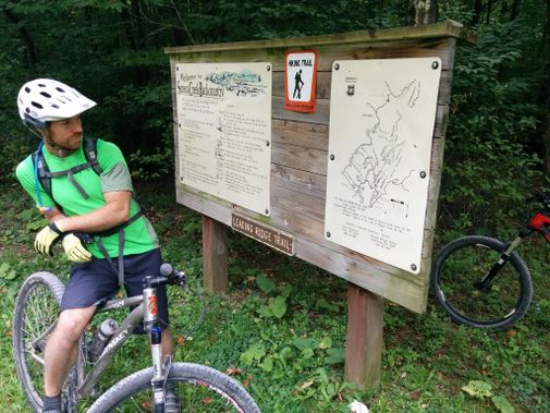A mountain biker at a Seneca Creek Trail sign