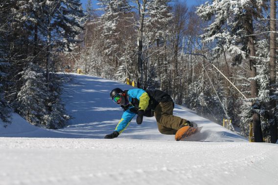 A snowboarder carves down the slope