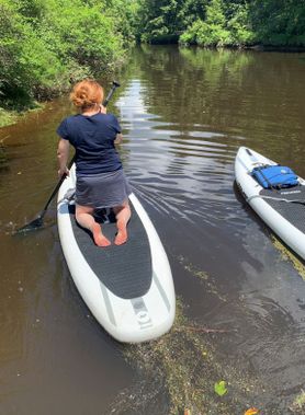A person on a SUP begins their paddle on the Blackwater River