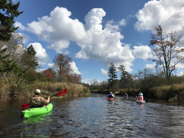 Kayaks move along the Blackwater River with big puffy clouds in the sky