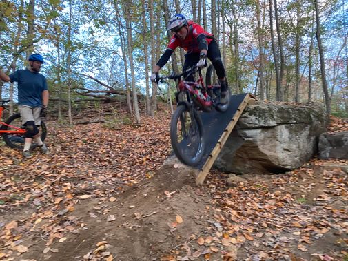 A mountain biker rides a rock feature at Upshur County Trails