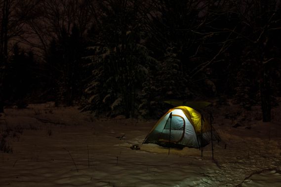 A tent is lit up in the winter darkness