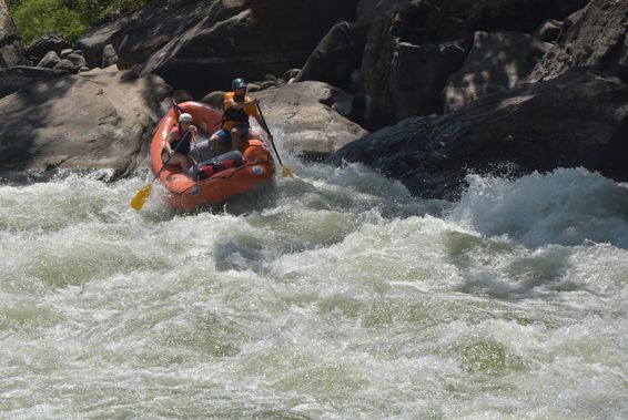 A raft pushed up against a wall of rock in a New River Gorge rapid