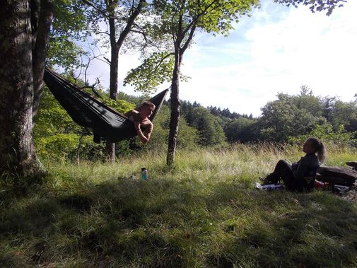 Two backpackers rest at camp, one in a hammock