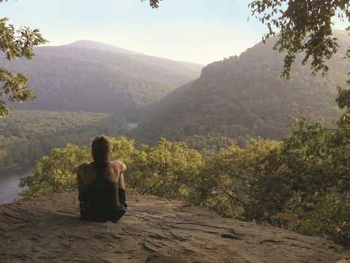 A person sitting on a rock looking out at the view