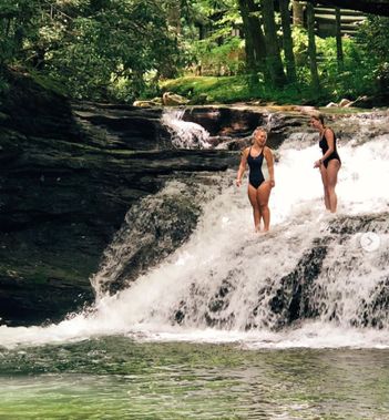 Two people get ready to jump into a swimming hole