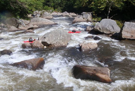 Kayakers navigate a tight boulder garden on the Upper Yough