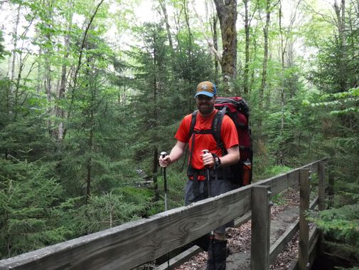 A backpacker crosses a bridge in Tea Creek